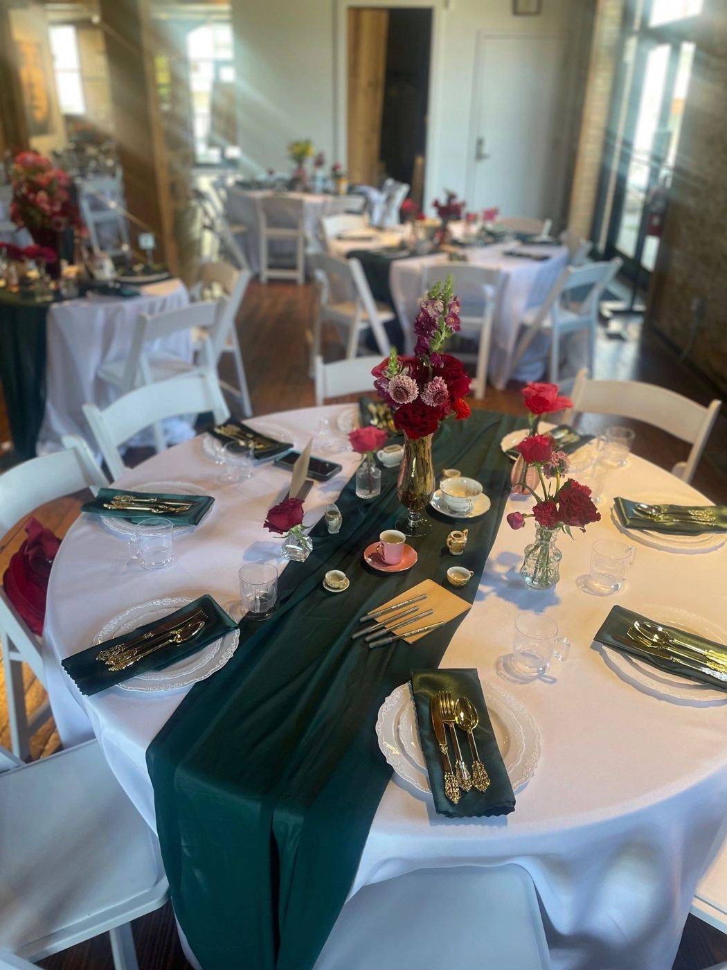Wedding table with a forest green runner and red florals
